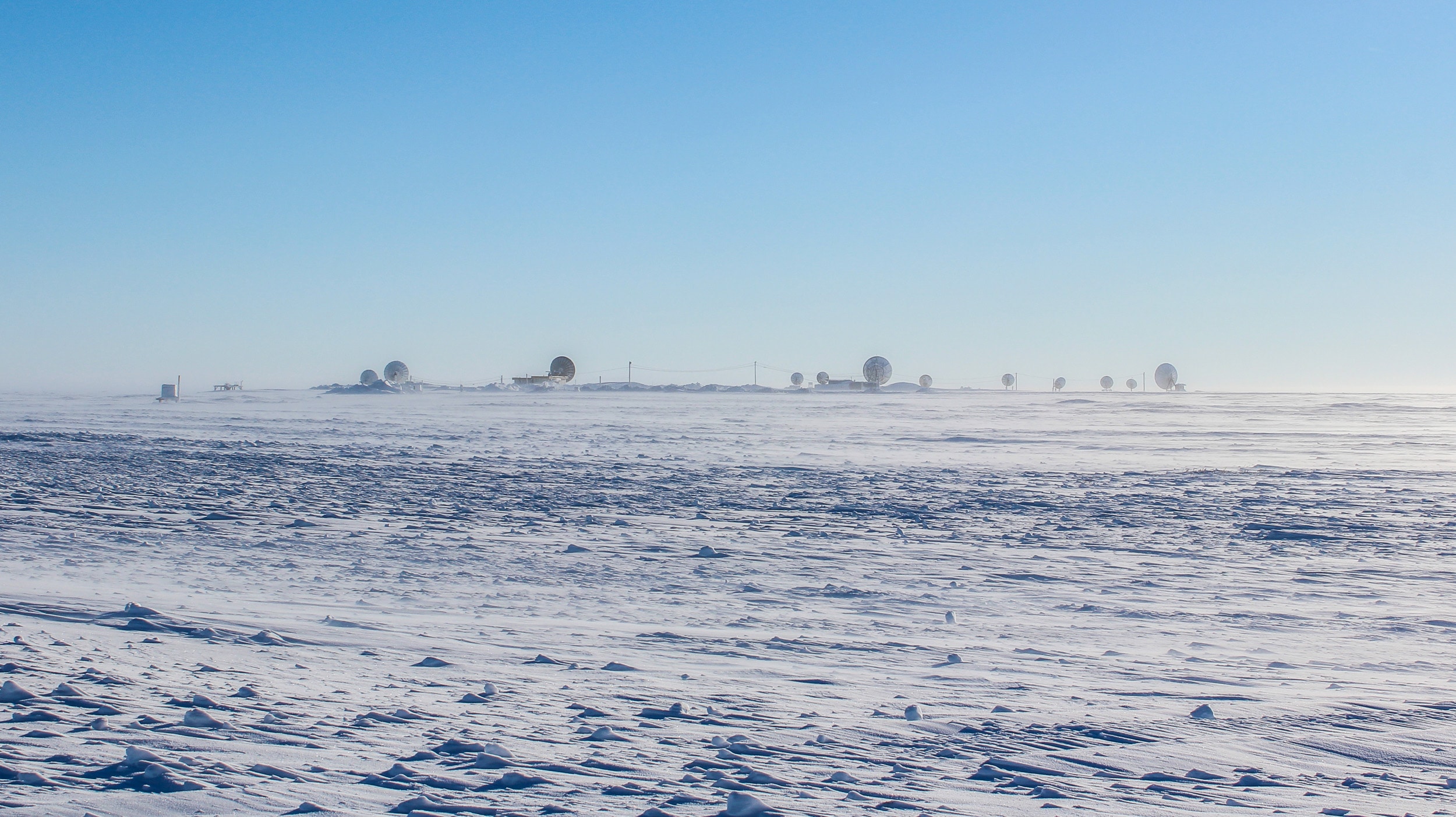 Arctic landscape of frozen coastal tundra in Barrow, Alaska, with satellite antennas in the background