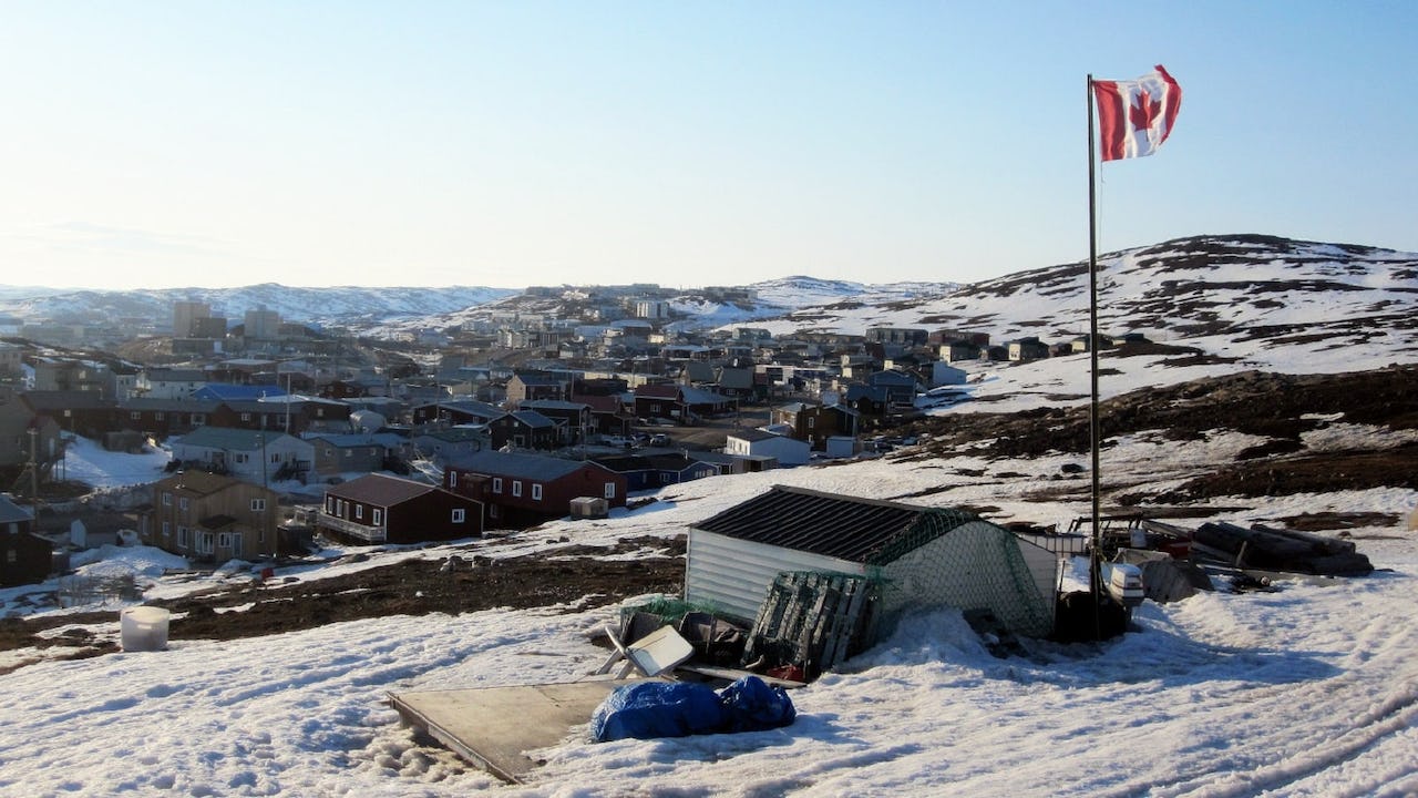 A Canadian flag flies over the city of Iqaluit, Nunavut which is covered in snow