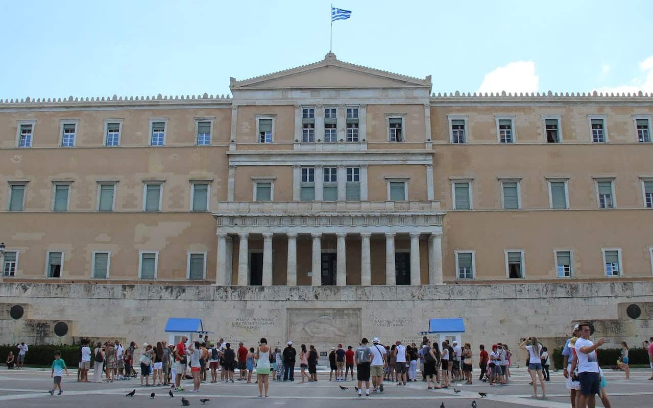 Hellenic Parliament of Greece in Athens with people standing on a square in front of it