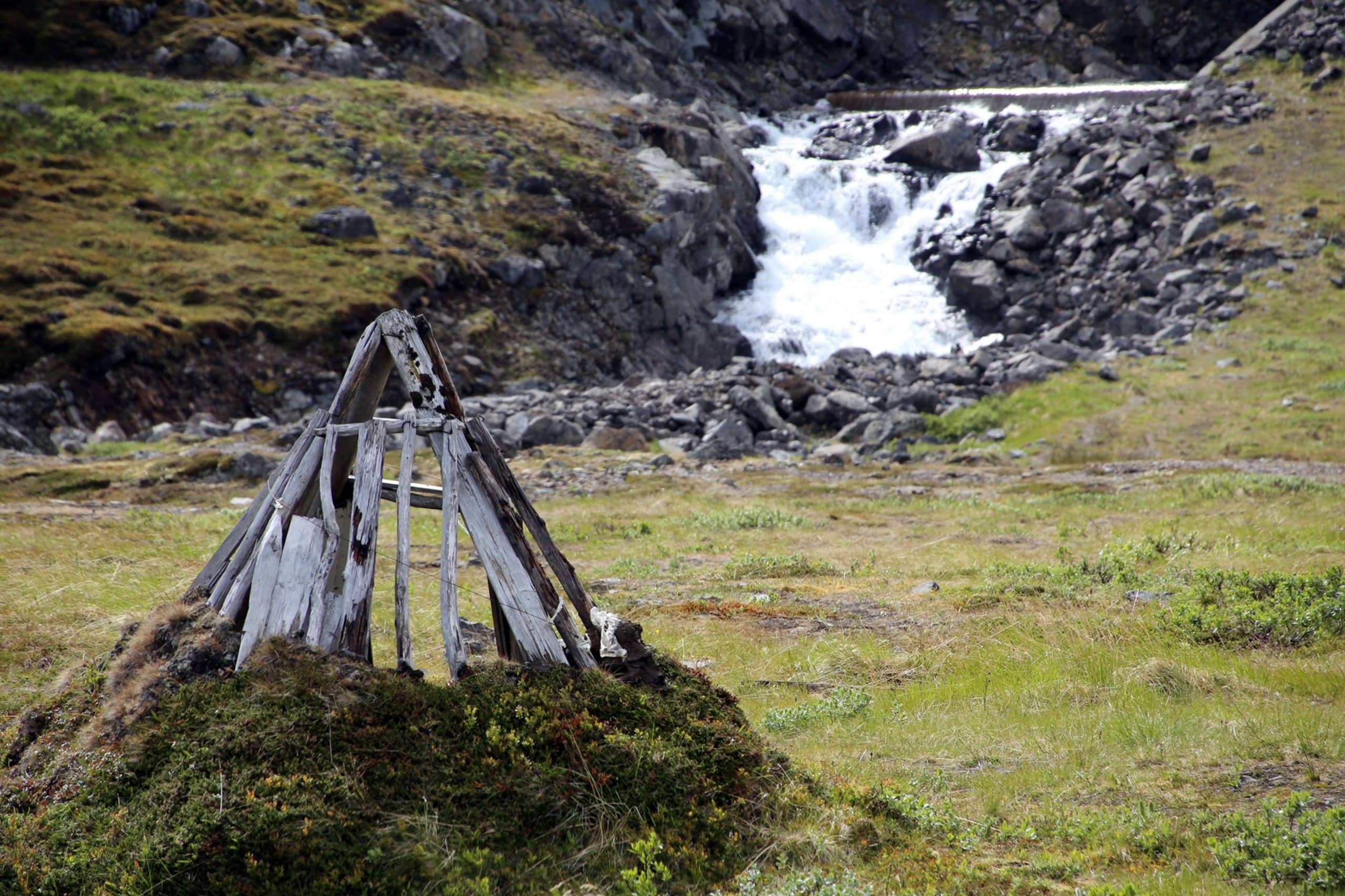 Wodden Sami hut skeleton in Finnmark, Norway, with falling river in the back
