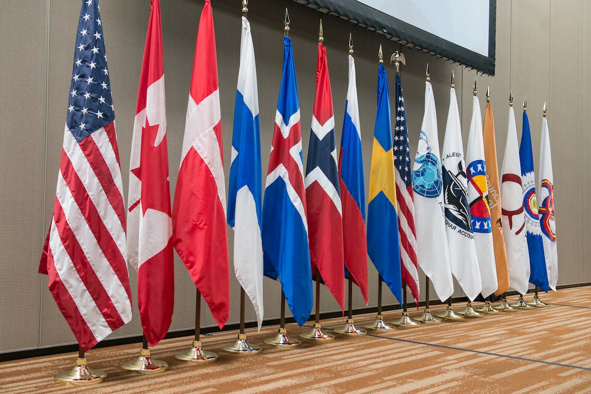 Flags of Finland, Canada, Denmark, Iceland, Norway, Russia, Sweden, United States, Arctic Council, and Indigenous peoples organizations stand at an event in Anchorage, Alaska 20-22 October 2015