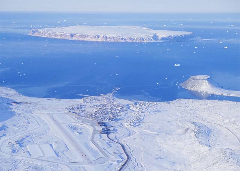 An aerial view of Pituffik Space Base in northern Greenland shows the runway, military facilities, Arctic waters, and surrounding polar landscape