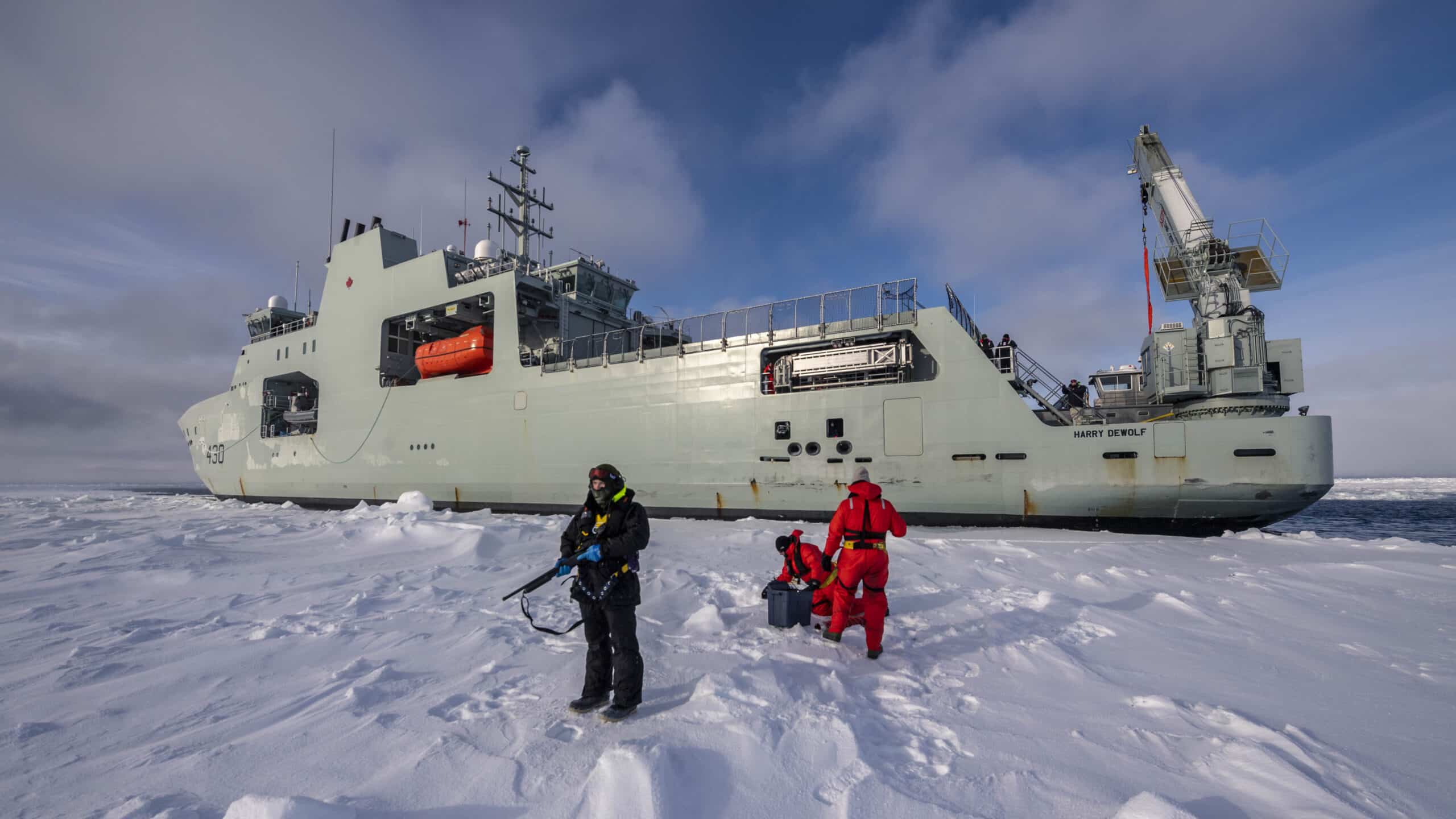 Royal Canadian Navy military ship in the Arctic, next to snow and man holding a gun