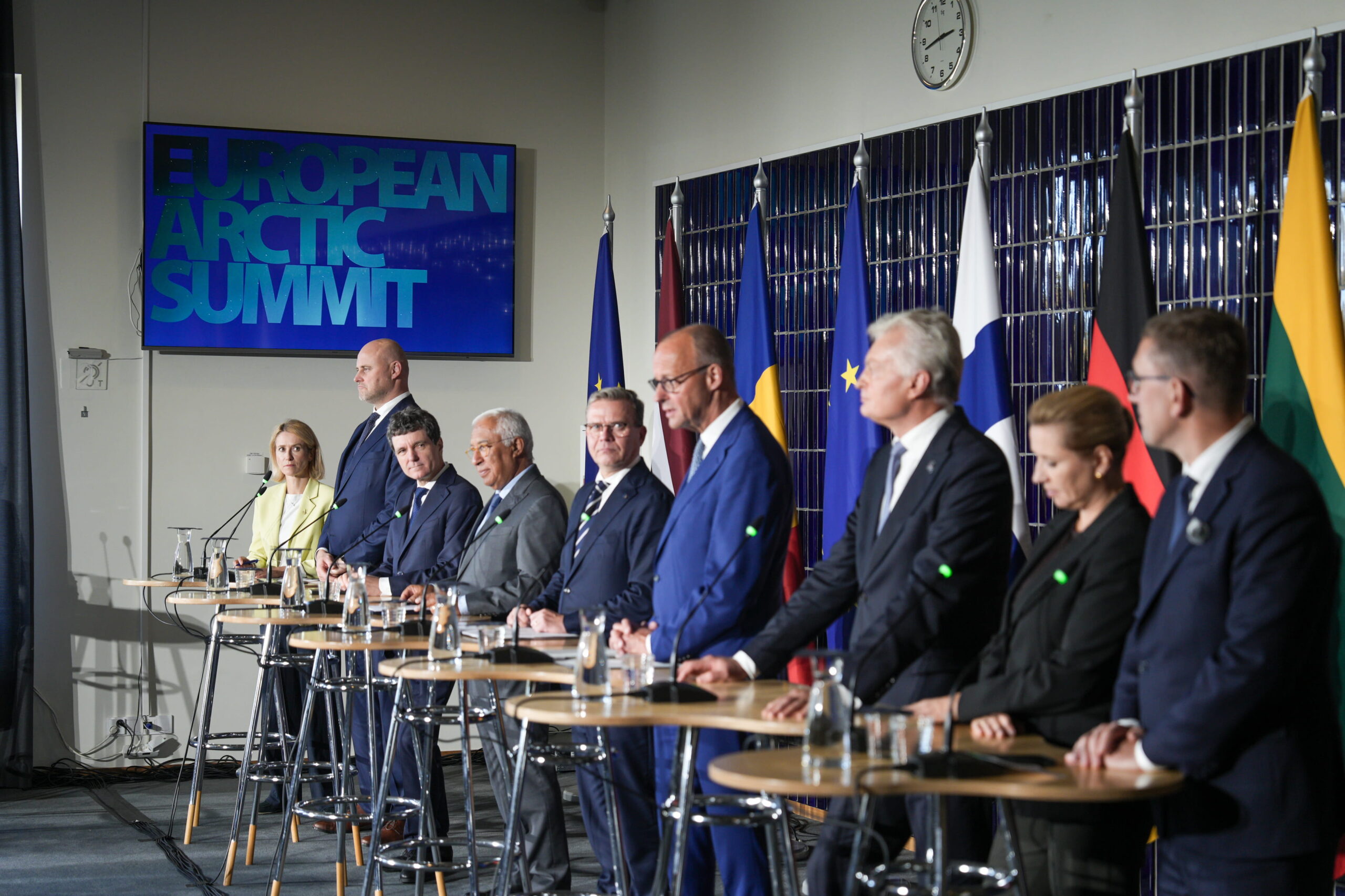 European Arctic Summit delegates seated at a press conference table with national and European Union flags in the background, discussing Arctic policy and international cooperation
