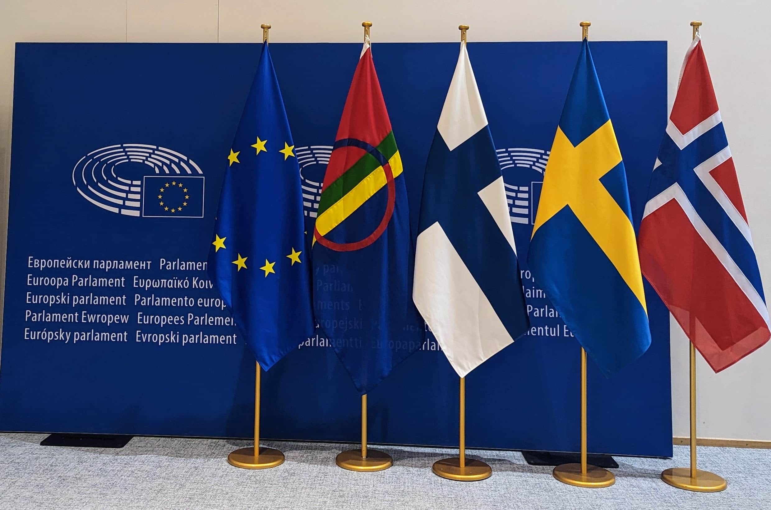 Flags of the European Union, Sápmi/Sami people, Finland, Sweden and Norway in front of European Parliament background logo