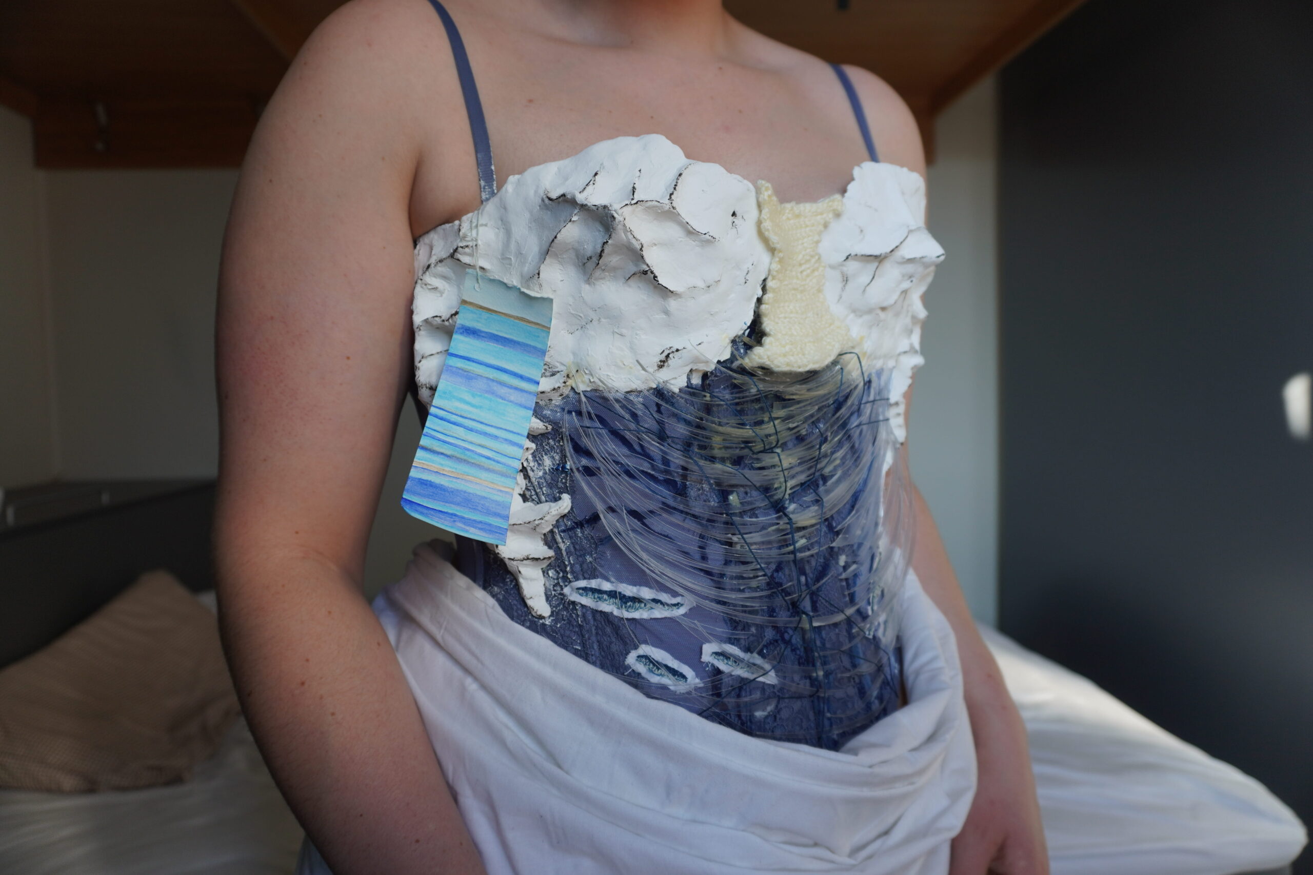 A woman wearing a fashion corset sculpted from clay, plastic, and fabric to resemble a glacial environment