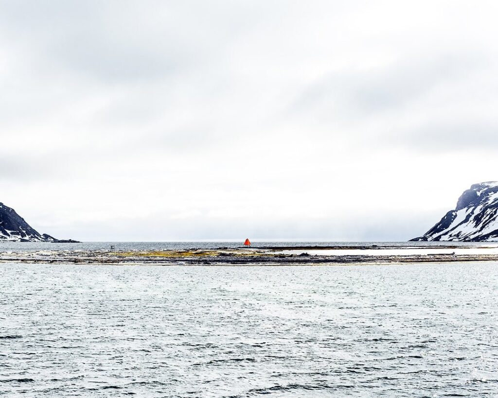 An blaze orange hazard warning in the Svalbard landscape with a light blue sky