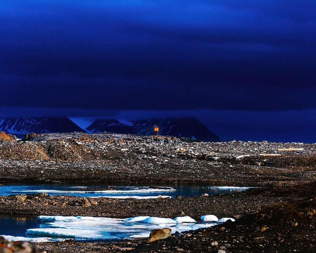 An blaze orange hazard warning in the Svalbard landscape with a dark blue sky