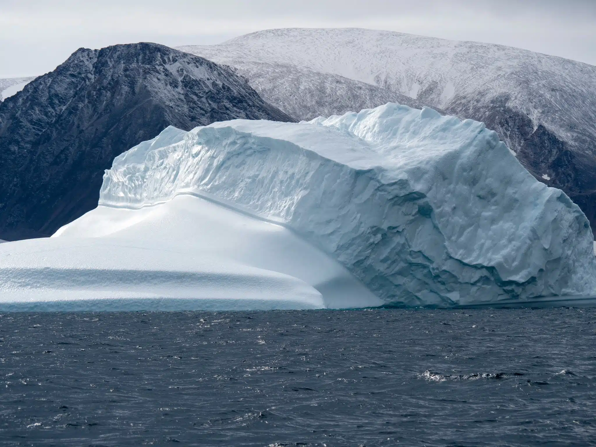 An iceberg in front of a mountainous landscape