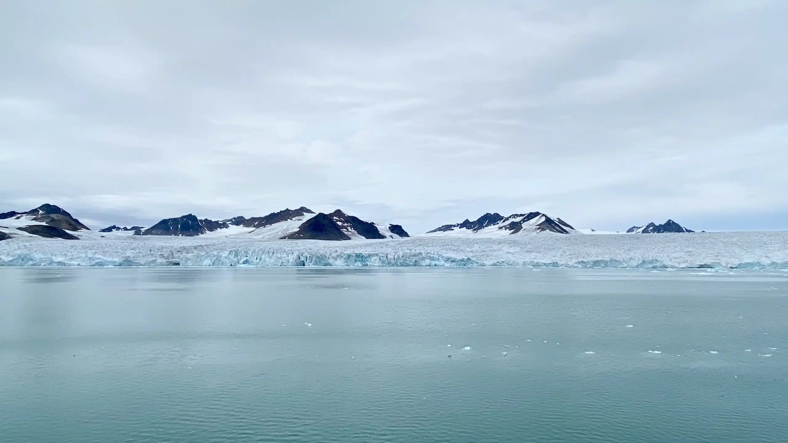A tidewater glacier is in front of mountains in Svalbard.