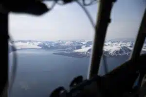 A C-130J Hercules plane flying over dark water and ice