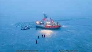 A gray and orange scientific station on blue ice