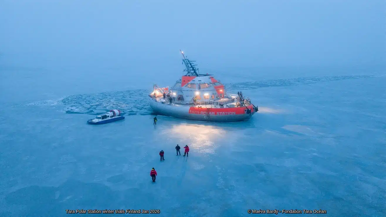 A gray and orange scientific station on blue ice