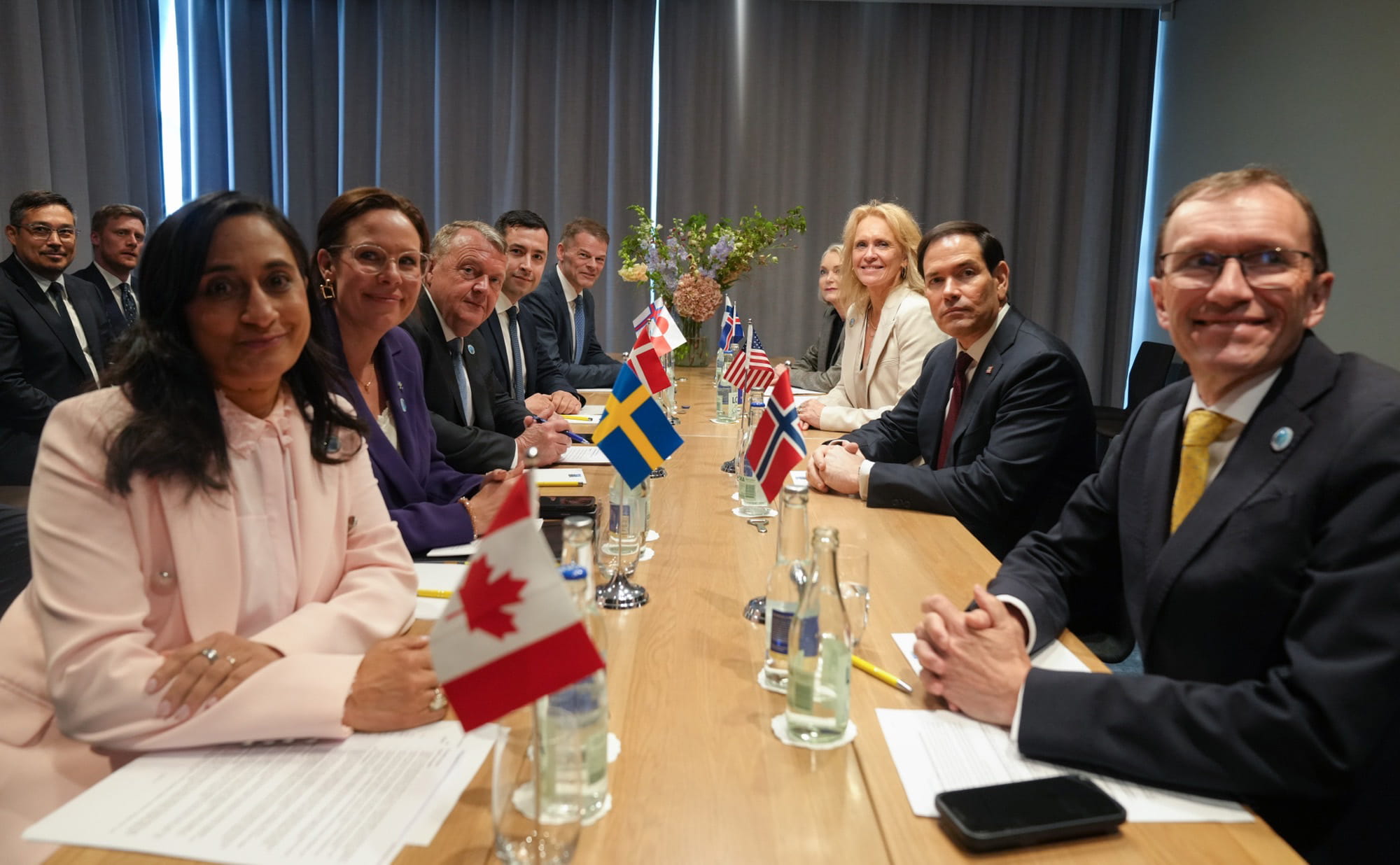 Delegates from Arctic Seven countries meet around a conference table with national flags during a diplomatic meeting in Helsingborg