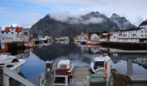 Fishing boats moored in Henningsvær harbour with steep, cloud-covered mountains behind them
