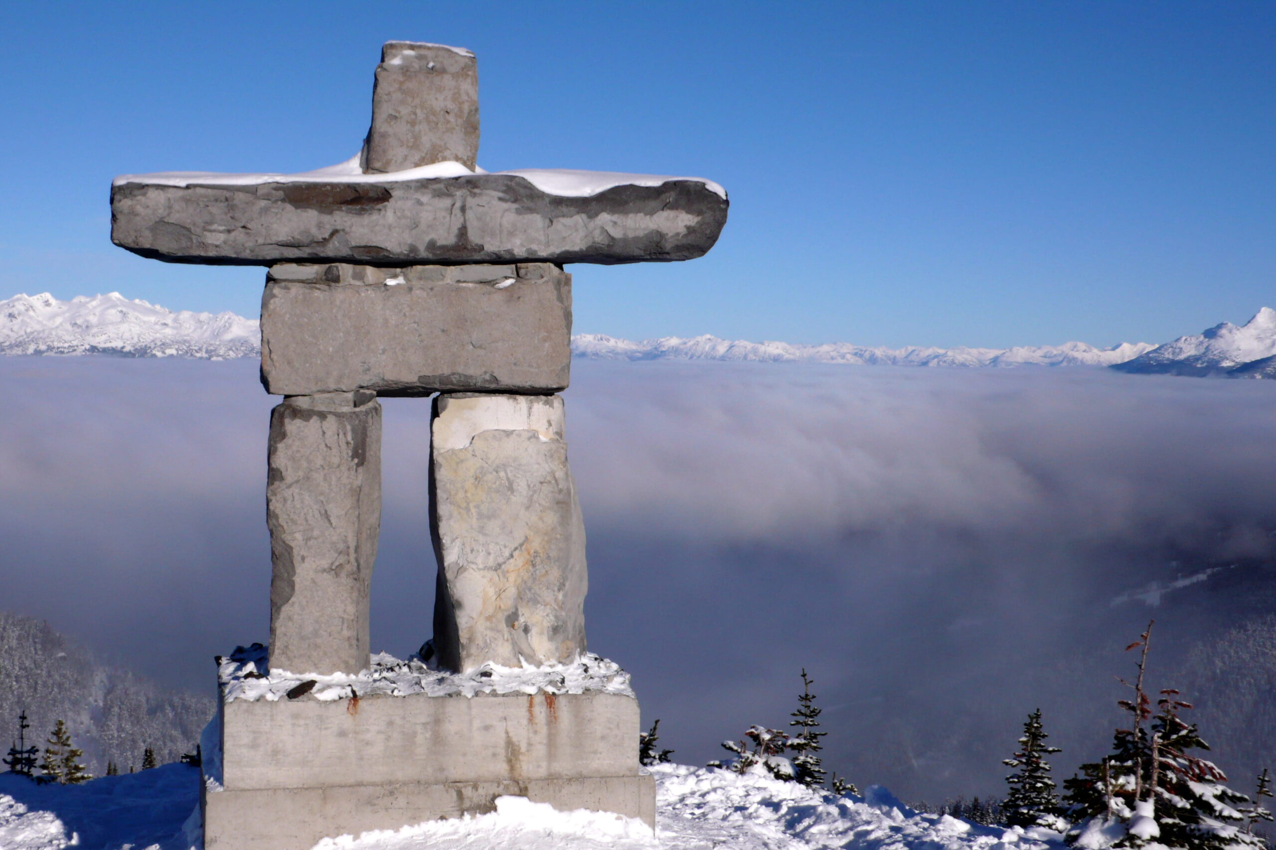 Inuit inukshuk stone monument overlooking a snowy Arctic mountain landscape in winter