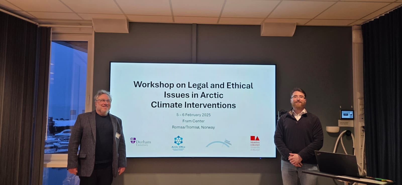 Two researchers at a workshop on legal and ethical issues in Arctic climate interventions, held on 5–6 February 2025 at the Fram Centre in Tromsø, Norway, with Durham University and Arctic Office logos displayed on the presentation screen